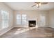 Spacious living room features a fireplace, ceiling fan, wood floors, and lots of natural light at 12584 Jessica Pl, Charlotte, NC 28269