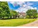 Beautiful landscaped yard with large shade trees, a brick and siding home, and blue sky at 1765 Old Clay Hill Rd, York, SC 29745