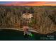 An aerial shot captures the estate and its private dock amidst a setting of bare winter trees and colorful dusk sky at 296 Windemere Isle Rd, Statesville, NC 28677