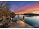 Sunset view of dock featuring Adirondack chairs and table, with lights reflecting on the water at 296 Windemere Isle Rd, Statesville, NC 28677