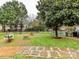 Backyard featuring lush greenery, a hammock, mature trees, a fire pit, and a paved stone walkway at 3300 Chancellor Ln, Monroe, NC 28110