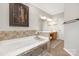 Bright primary bathroom with tiled walls, soaking tub, framed art, and vanity area at 3300 Chancellor Ln, Monroe, NC 28110