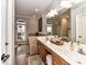 Bathroom featuring a large vanity with dual sinks, a window view, and decorative rugs at 3300 Chancellor Ln, Monroe, NC 28110