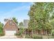 Front view of brick house with white garage doors, a charming porch, and a well-manicured lawn at 3300 Chancellor Ln, Monroe, NC 28110