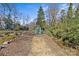 Backyard with gravel path leading to storage, surrounded by mature trees and greenery at 3723 Annlin Ave, Charlotte, NC 28209