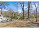 Backyard featuring a patio with seating, an outdoor fireplace, and a spacious grassy area surrounded by trees at 3723 Annlin Ave, Charlotte, NC 28209