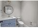 Stylish powder room with blue vanity, gold accents, and a round mirror at 3945 Ostler Ct, Lancaster, SC 29720