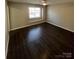 Spacious bedroom with dark wood-look flooring, a ceiling fan and a large bright window at 5956 Prescott Ct, Charlotte, NC 28269