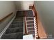 Carpeted staircase with wood railing in a well-lit home featuring carpeted treads and white risers at 5956 Prescott Ct, Charlotte, NC 28269