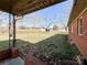 View of the expansive backyard, featuring brick home, storage shed, and covered patio at 6523 Prospect Rd, Monroe, NC 28112