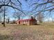 Exterior view of brick home with a red metal roof surrounded by lawn and mature trees at 6523 Prospect Rd, Monroe, NC 28112