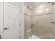 Modern walk-in shower featuring neutral tile, decorative stripe, glass door and a built-in seat, combining style and functionality at 232 Parkwood Ave, Charlotte, NC 28206