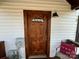 Charming front door with exterior sconce and chair with decorative pillow at 3186 Catawba St, Claremont, NC 28610