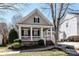 Charming home with a welcoming front porch, complemented by manicured landscaping and mature trees under a bright blue sky at 319 Ohenry Ave, Davidson, NC 28036