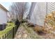 Landscaped side yard with a stone walkway, black fence, and flowering bushes at 319 Ohenry Ave, Davidson, NC 28036