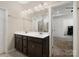 Bathroom featuring dark cabinets, double sinks, a large mirror, and open door to the bedroom at 6351 Trinity Crossing Cir, Kannapolis, NC 28081