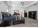 Spacious main bedroom featuring a tray ceiling, ceiling fan, large bed, and elegant decor at 6351 Trinity Crossing Cir, Kannapolis, NC 28081
