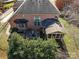 A high-angle shot of a brick house, back patio, screened porch, and lush surrounding greenery at 11402 Bloomfield Dr, Charlotte, NC 28277