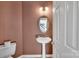 Powder room featuring a pedestal sink, oval mirror, and neutral paint, adding convenience for guests at 11402 Bloomfield Dr, Charlotte, NC 28277