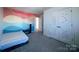 Comfortable bedroom featuring colorful wall murals, plush carpeting, and ample closet space with rainbow decoration at 12712 Wandering Brook Dr, Charlotte, NC 28273