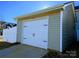 Exterior shot of a detached garage with a white door and light beige siding, under a clear blue sky at 12712 Wandering Brook Dr, Charlotte, NC 28273