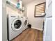 Modern laundry room with washer and dryer, shelving, and wood-look flooring at 12712 Wandering Brook Dr, Charlotte, NC 28273