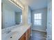 Bathroom featuring an extended vanity, large mirror, and a bright window at 13410 Tartarian Ct, Charlotte, NC 28215