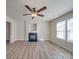 Open living area with a corner fireplace, ceiling fan, hardwood floors, and window at 13410 Tartarian Ct, Charlotte, NC 28215