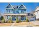 Charming two-story blue home featuring a welcoming front porch with stone columns and manicured landscaping at 520 Crawfish Dr, Fort Mill, SC 29708