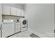 Well-lit laundry room includes white cabinets, washer, and dryer at 520 Crawfish Dr, Fort Mill, SC 29708