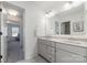 Bright bathroom with double sinks, grey cabinets, a large mirror, and a door to a second bathroom at 7019 Lenton Rd, Charlotte, NC 28215