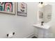 Charming powder room featuring a pedestal sink, decorative mirror, modern faucet, stylish artwork, and dark fixtures at 7019 Lenton Rd, Charlotte, NC 28215