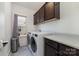Functional laundry room with front load washer and dryer, dark cabinets, and a gray countertop at 7019 Lenton Rd, Charlotte, NC 28215