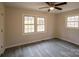 Bright bedroom featuring gray laminate floors, modern ceiling fan, and double-paned windows at 833 E Chestnut St, Stanley, NC 28164