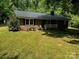 Charming brick home with a metal roof, front porch, and lush green lawn at 833 E Chestnut St, Stanley, NC 28164