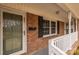 Charming front porch with brick facade, white railing, and a storm door at 833 E Chestnut St, Stanley, NC 28164