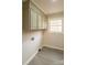 Neat laundry area features cabinets above washer hookups and a window for natural light at 833 E Chestnut St, Stanley, NC 28164