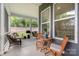 A cozy screened in patio with comfortable seating, a table, and outdoor views of the backyard at 119 Winterberry St, Mooresville, NC 28117