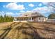 Rear view of a tan stucco home highlighting the covered patio, landscaped yard and architectural details at 148 Castle Dr, Mooresville, NC 28117