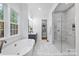 Bright bathroom features a soaking tub, walk-in shower with glass door, marble floors and large windows at 19155 Newburg Hill Rd, Davidson, NC 28036