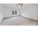 Bright bedroom features neutral carpeting, a ceiling fan, and a window overlooking the backyard at 19155 Newburg Hill Rd, Davidson, NC 28036
