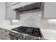 Close-up of a high-end stainless steel gas range top, quartz countertops, and a tile backsplash at 19155 Newburg Hill Rd, Davidson, NC 28036