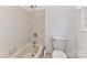 Neutral bathroom featuring a tub-shower combo, toilet, neutral tiles, and a small window at 2050 Tite Rd, Stanfield, NC 28163