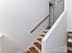 Staircase with wooden steps and white risers with a wooden handrail along the wall at 2050 Tite Rd, Stanfield, NC 28163