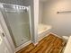 Clean bathroom with shower, tub, and wood-look floors at 257 Doughton Ln, Charlotte, NC 28217