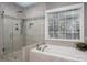 Luxurious bathroom featuring a glass-enclosed shower and a soaking tub with window views at 1005 Antioch Woods Ln, Matthews, NC 28104