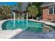 A backyard pool surrounded by stone with a pergola alongside a brick home at 1005 Antioch Woods Ln, Matthews, NC 28104