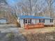 White single-story home with blue metal roof, deck, and wooded lot at 1075 Fye Dr, Newton, NC 28658