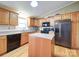 Functional kitchen featuring wood cabinets, a center island, black appliances, and plenty of counter space and natural light at 1075 Fye Dr, Newton, NC 28658