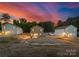 Three modern homes sit on a grassy lot under a beautiful sunset with orange and blue colors at 1132 Thayer Glen Ct, Charlotte, NC 28213